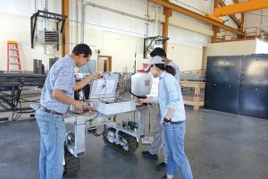 Manoj Karkee (left) and two graduate students inspect an automatic control system that guides the weeding robot through the field.